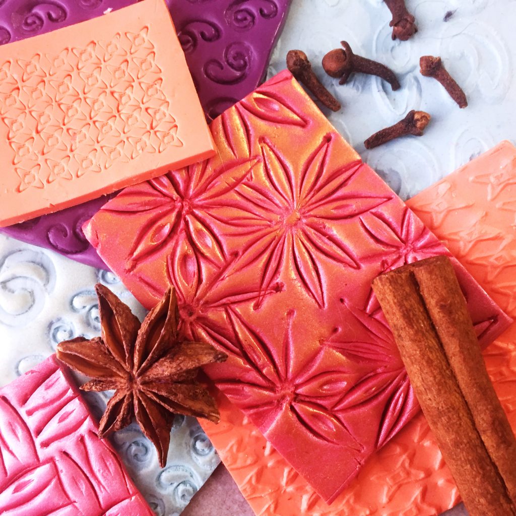 sheets of polymer clay embossed with textures made from household spices, including whole cloves, cinnamon and star anise