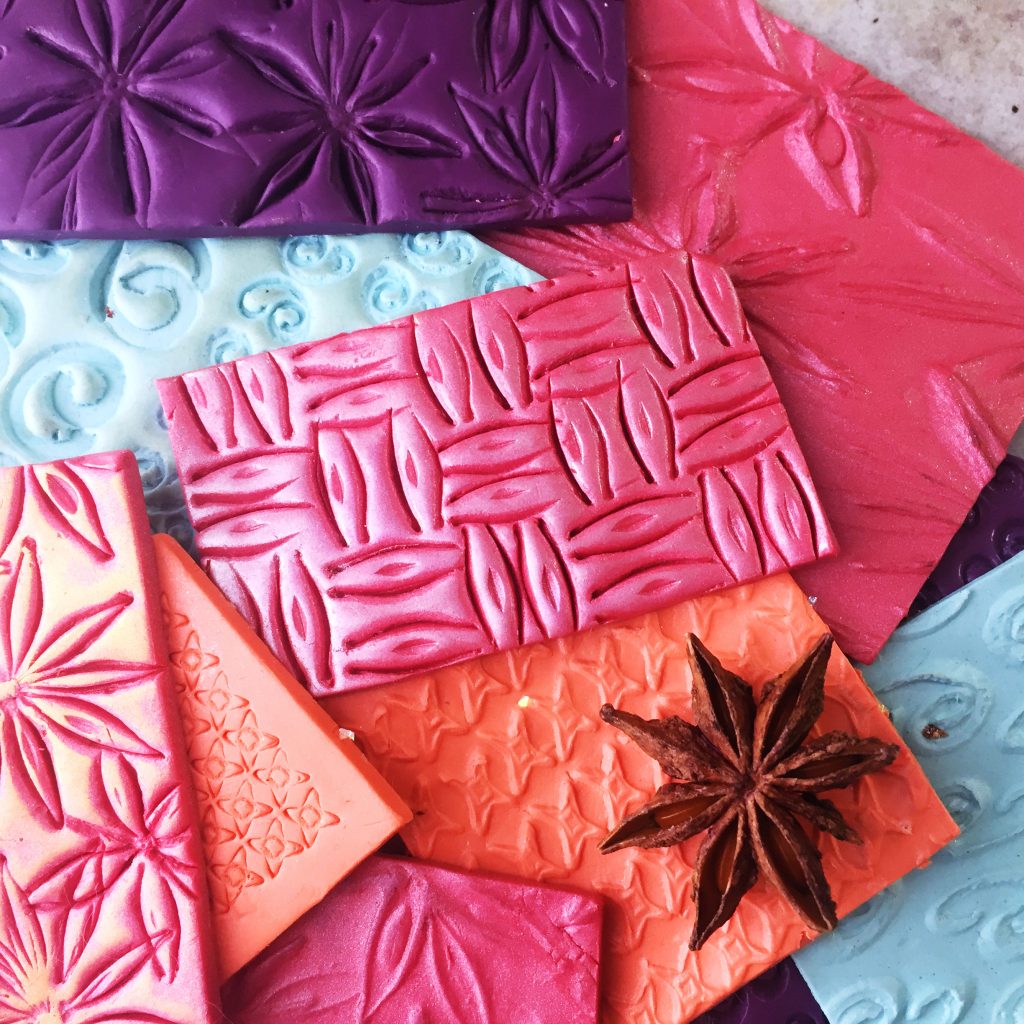 sheets of polymer clay embossed with textures made from household spices, including star anise