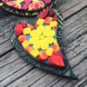 heart shape cut out of mandala designs in yellow, red and orange colors made with polymer clay