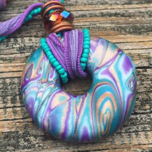 This purple, blue and copper mokume gane donut pendant was the first polymer clay piece that I sanded and buffed.
 You can see in the photo how buffing brings out depth and sparkle in the metallic clay. 