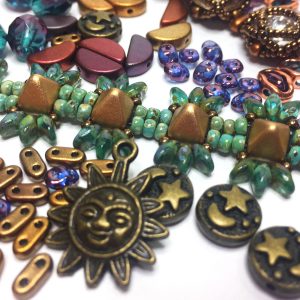 Seed beads from the January 2020 Potomac bead box, including pyramid beads, two-hole bar beads, a sun charm, moon and stars metal beads and superduo