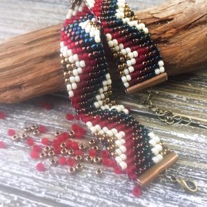 a zigzag patterned bead bracelet in red, white, gold, bronze and blue made with a beading loom and 8/0 seed beads