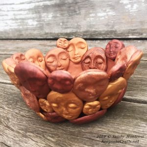 trinket bowl assemblage, a bowl covered with molded polymer clay faces